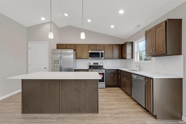 kitchen featuring sink, light hardwood / wood-style flooring, backsplash, stainless steel appliances, and decorative light fixtures