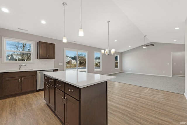 kitchen featuring sink, dishwasher, decorative light fixtures, vaulted ceiling, and light wood-type flooring