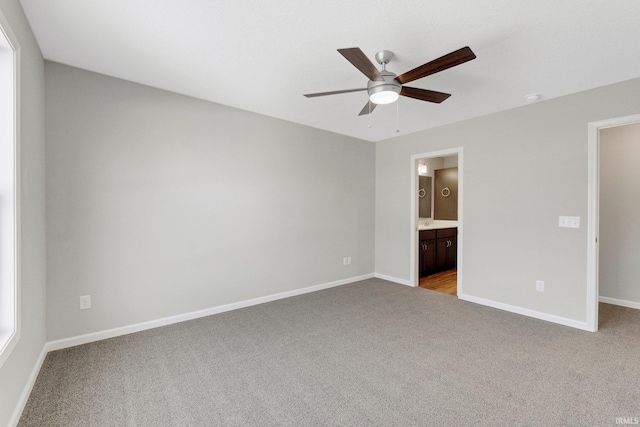 unfurnished bedroom featuring ceiling fan, ensuite bathroom, and light colored carpet