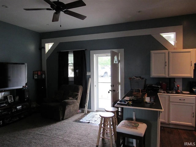 kitchen featuring white cabinetry, ceiling fan, a kitchen bar, and dark colored carpet