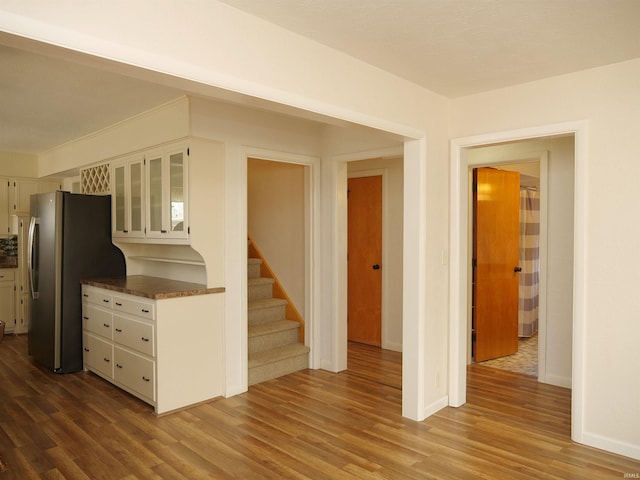 kitchen with hardwood / wood-style flooring, stainless steel fridge, and white cabinets