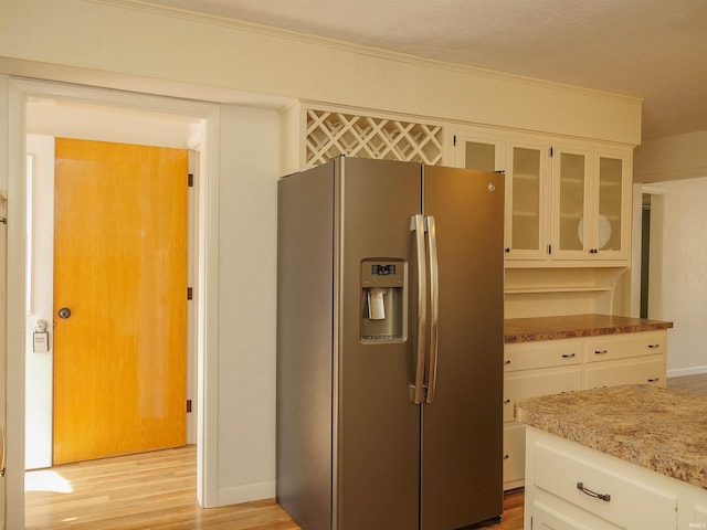 kitchen featuring white cabinetry, stainless steel fridge with ice dispenser, light hardwood / wood-style floors, and light stone countertops