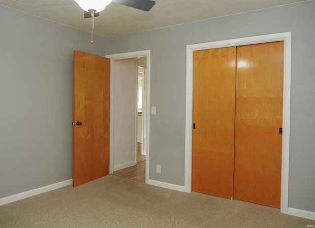 unfurnished bedroom featuring a textured ceiling, light colored carpet, a closet, and ceiling fan