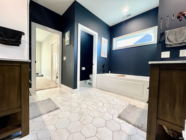 bathroom featuring a tub to relax in, vanity, and toilet