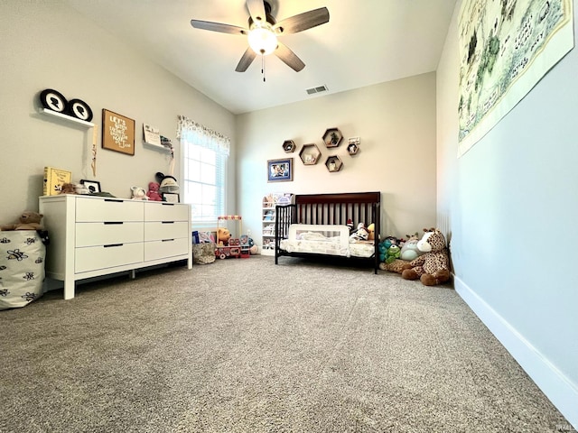 bedroom featuring a nursery area, ceiling fan, and carpet flooring