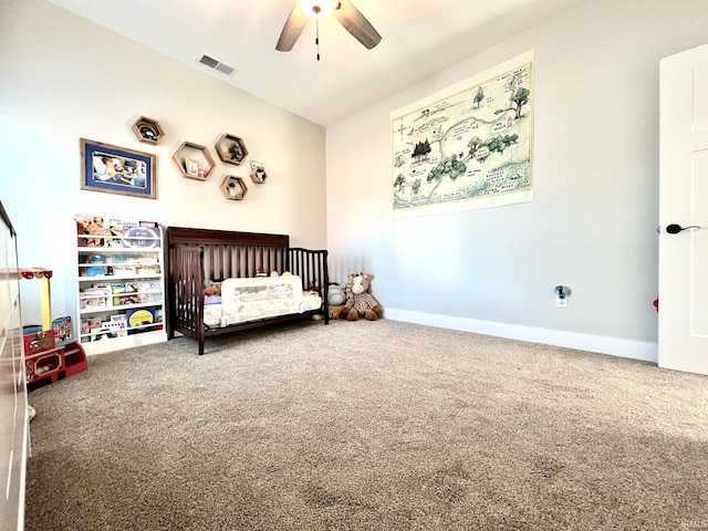 carpeted bedroom featuring a nursery area and ceiling fan