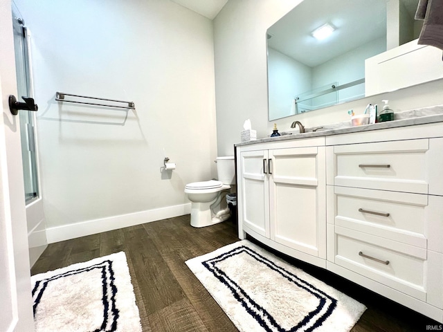 full bathroom featuring vanity, hardwood / wood-style flooring, enclosed tub / shower combo, and toilet