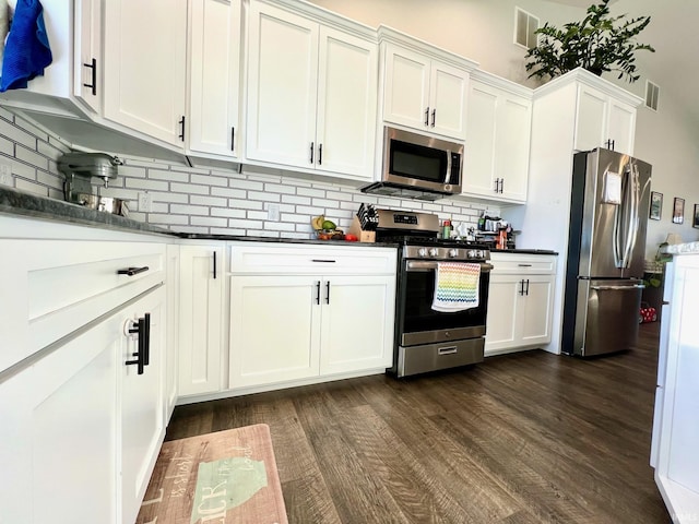 kitchen with dark hardwood / wood-style flooring, tasteful backsplash, white cabinets, and appliances with stainless steel finishes