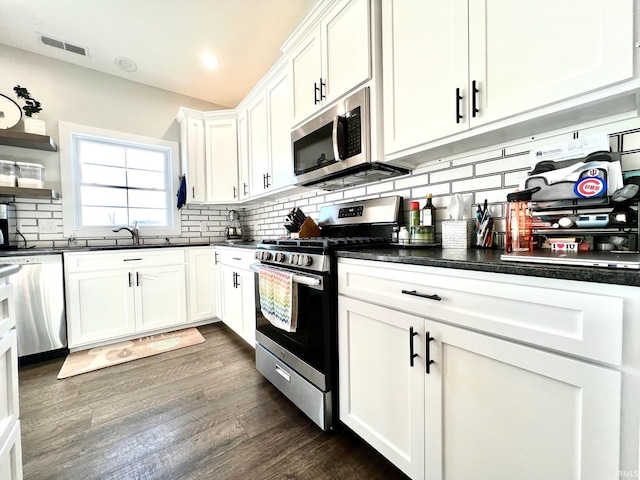 kitchen with sink, white cabinets, backsplash, stainless steel appliances, and dark wood-type flooring