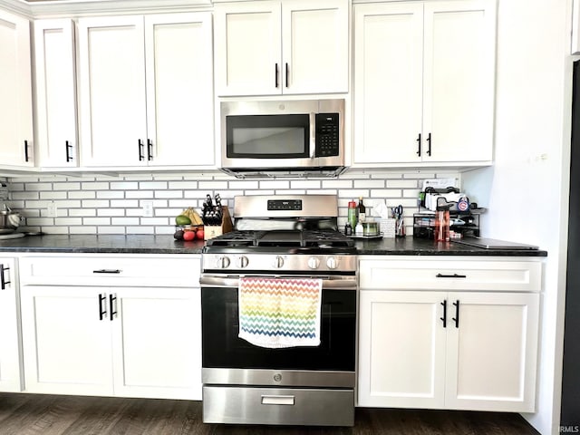 kitchen with backsplash, stainless steel appliances, dark stone counters, and white cabinets