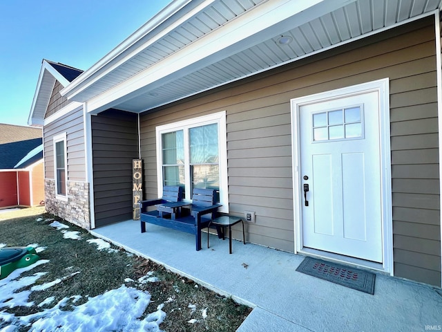 snow covered property entrance featuring a patio area