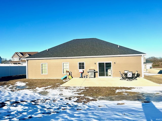 snow covered back of property with a patio area