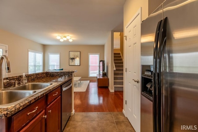 kitchen with dark stone countertops, sink, stainless steel appliances, and dark tile patterned floors