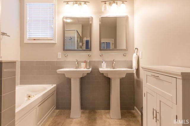 bathroom with double sink, tile patterned floors, tile walls, and a tub