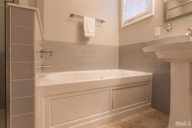 bathroom with tile patterned floors, a bath, and tile walls