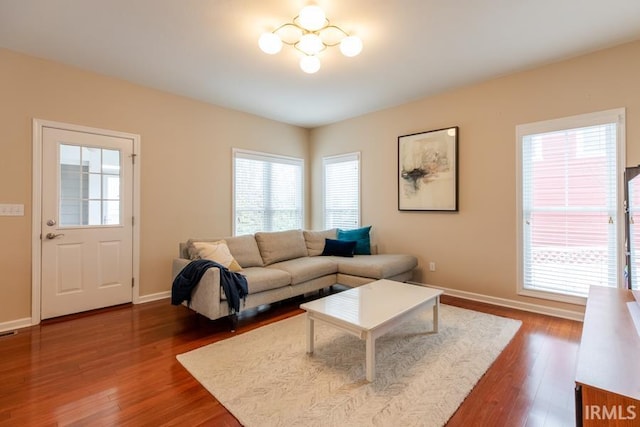 living room with a wealth of natural light, dark wood-type flooring, and a chandelier