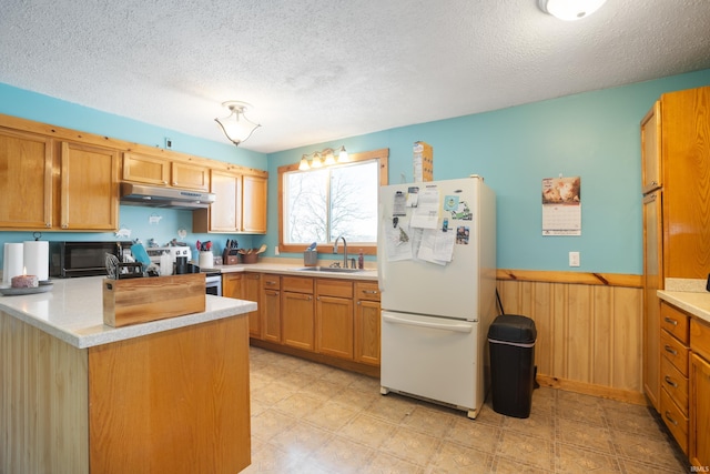 kitchen with sink, stainless steel range with electric cooktop, white refrigerator, kitchen peninsula, and a textured ceiling