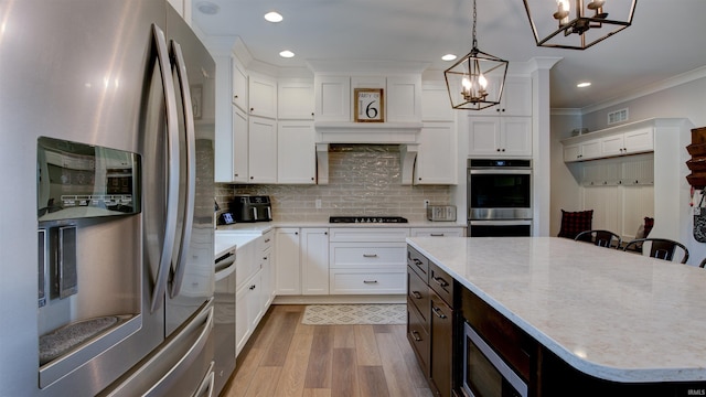 kitchen with pendant lighting, a breakfast bar area, appliances with stainless steel finishes, a center island, and white cabinets