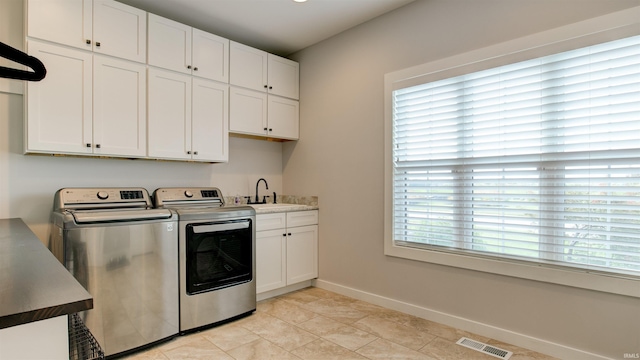 washroom featuring sink, light tile patterned floors, washing machine and dryer, and cabinets