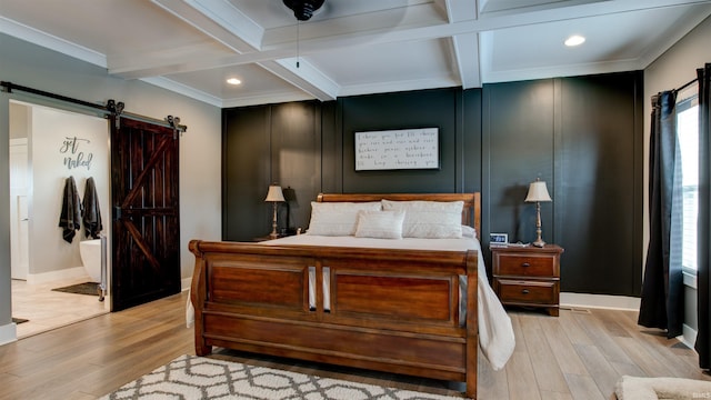 bedroom featuring light hardwood / wood-style floors, a barn door, and beamed ceiling