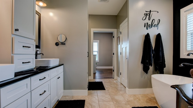 bathroom featuring vanity, a healthy amount of sunlight, a bath, and tile patterned floors