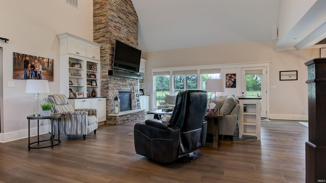 living room with dark hardwood / wood-style flooring, a stone fireplace, plenty of natural light, and high vaulted ceiling