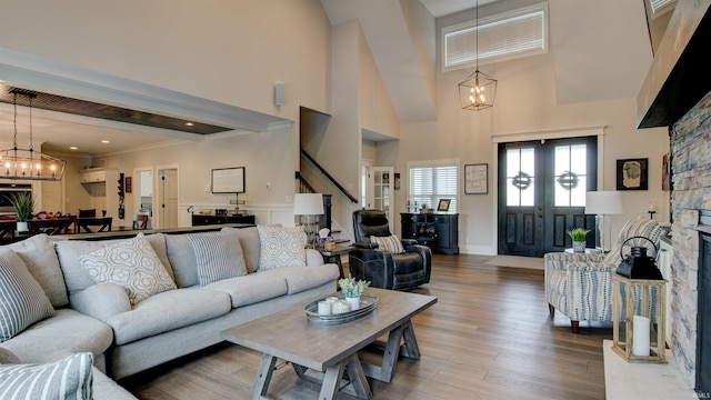 living room with an inviting chandelier, hardwood / wood-style floors, a fireplace, and a high ceiling