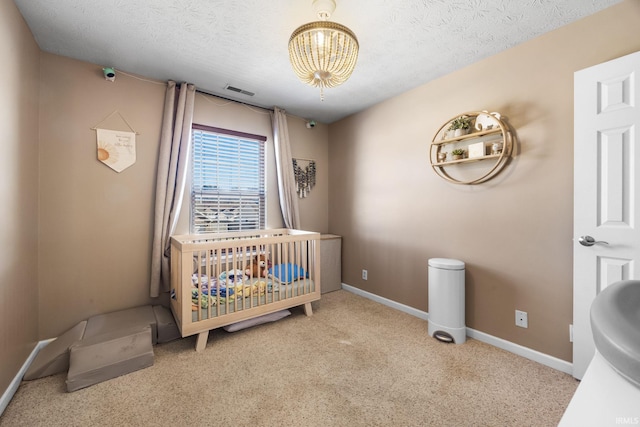 carpeted bedroom featuring a nursery area and a textured ceiling