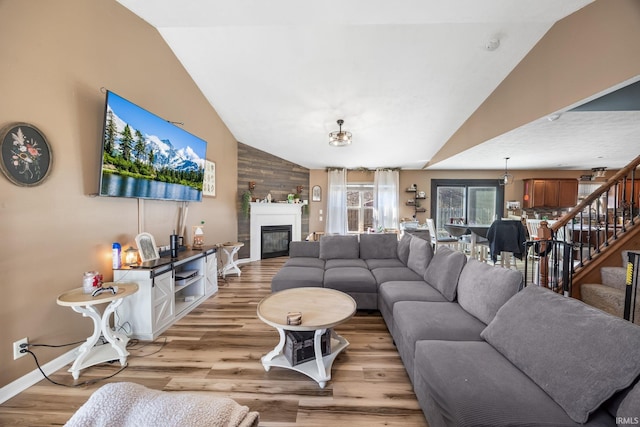 living room with lofted ceiling, light hardwood / wood-style flooring, and wood walls