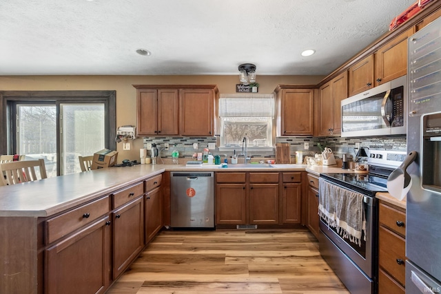 kitchen with stainless steel appliances, kitchen peninsula, sink, and a wealth of natural light