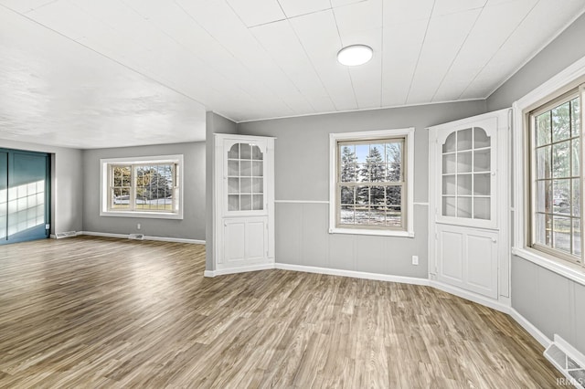 unfurnished room with vaulted ceiling, plenty of natural light, and light wood-type flooring