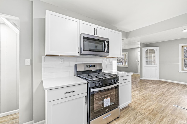 kitchen featuring backsplash, stainless steel appliances, light hardwood / wood-style floors, and white cabinets