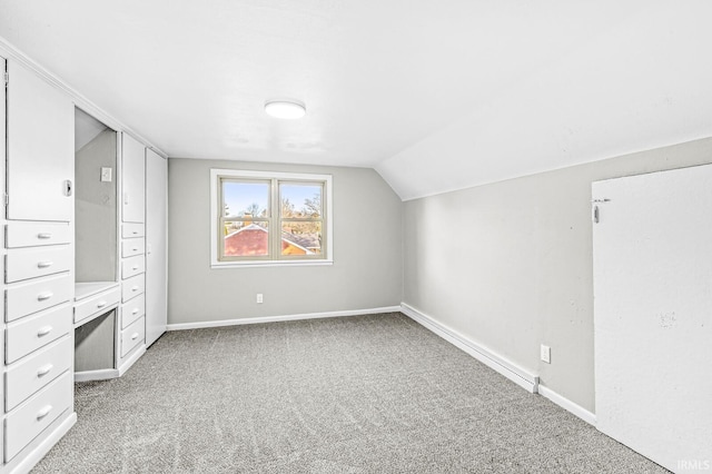 bonus room with vaulted ceiling and carpet