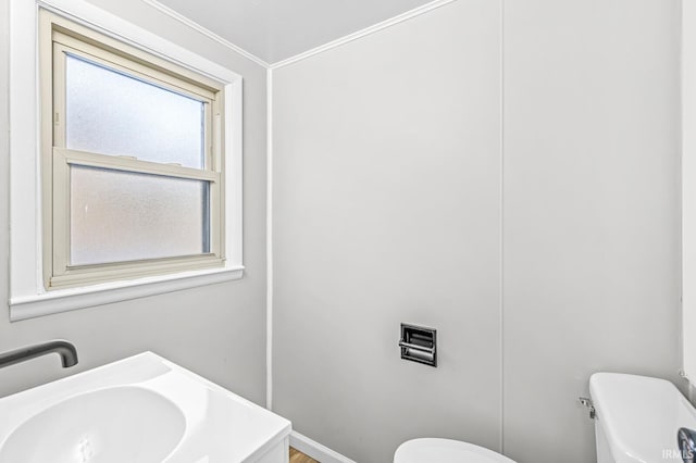 bathroom with ornamental molding, toilet, and sink