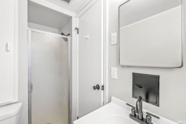 bathroom featuring an enclosed shower, sink, and toilet