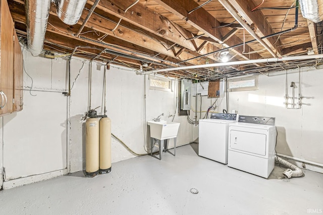 basement featuring independent washer and dryer, electric panel, and sink