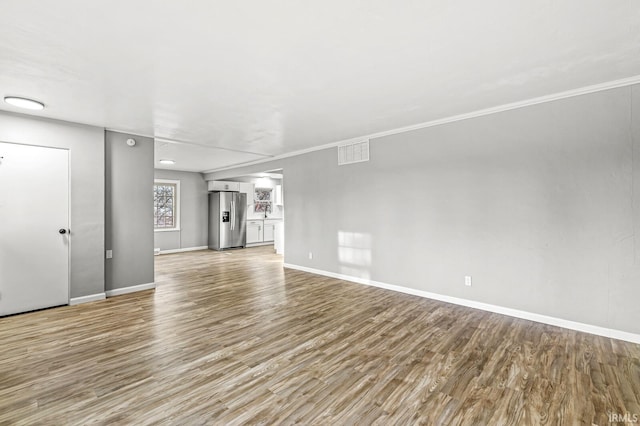 unfurnished living room featuring ornamental molding and light hardwood / wood-style flooring