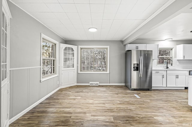 kitchen with tasteful backsplash, white cabinetry, sink, light hardwood / wood-style floors, and stainless steel refrigerator with ice dispenser