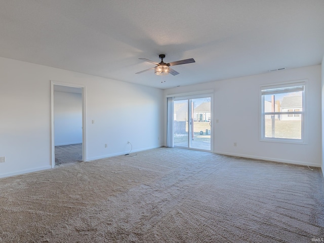 carpeted spare room featuring a wealth of natural light and ceiling fan