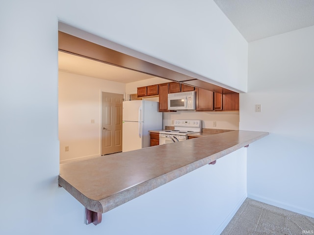 kitchen with a kitchen bar, light carpet, white appliances, and kitchen peninsula