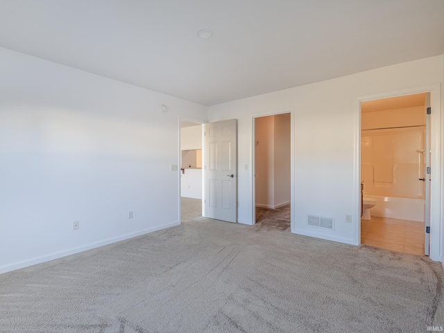 unfurnished bedroom featuring ensuite bathroom and light carpet