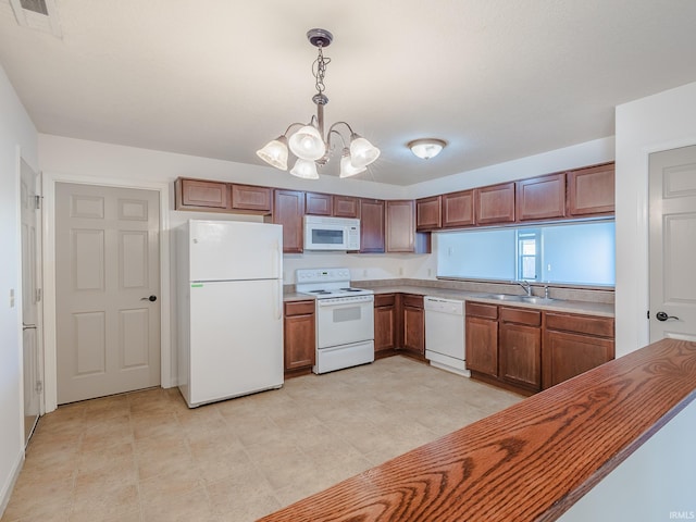 kitchen with pendant lighting, sink, white appliances, and a chandelier