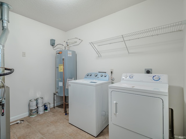 laundry area with electric water heater, a textured ceiling, and washer and clothes dryer