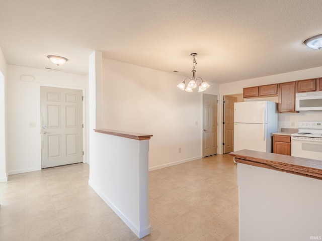 kitchen featuring pendant lighting, white appliances, and a chandelier