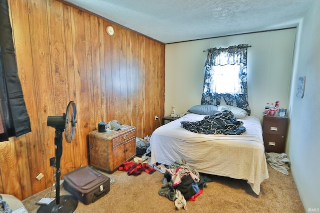 bedroom with wooden walls, a textured ceiling, and carpet flooring