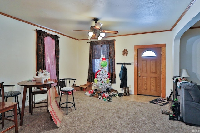 interior space featuring ceiling fan, ornamental molding, and a textured ceiling