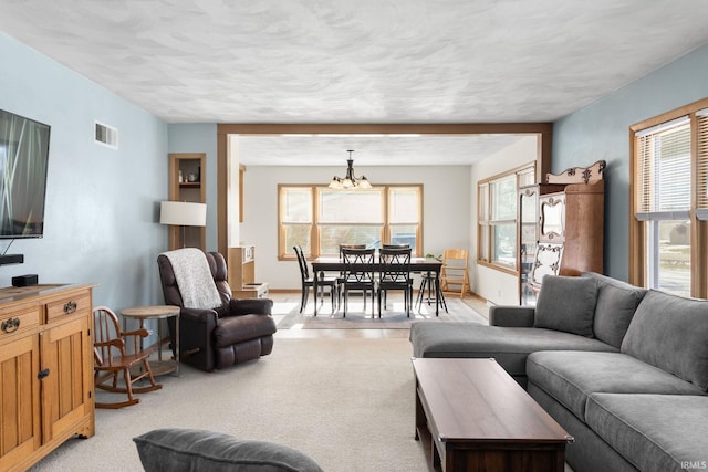 carpeted living room featuring an inviting chandelier