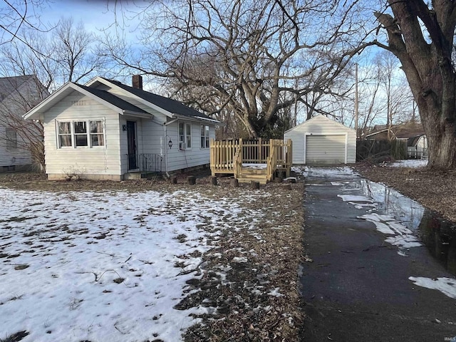 snow covered property with a garage and an outdoor structure