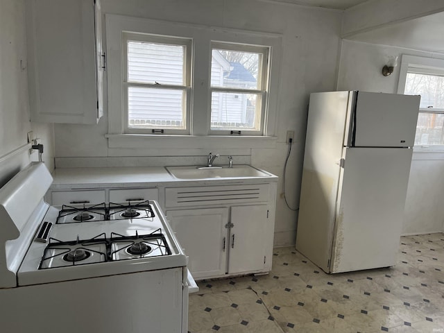 kitchen featuring white appliances, a healthy amount of sunlight, sink, and white cabinets