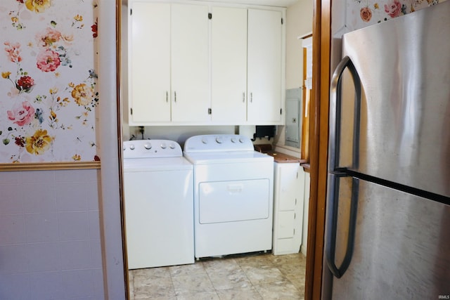 laundry room featuring cabinets, electric panel, separate washer and dryer, and tile walls